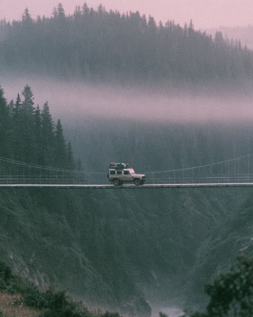A vehicle crossing a suspension bridge in fog.